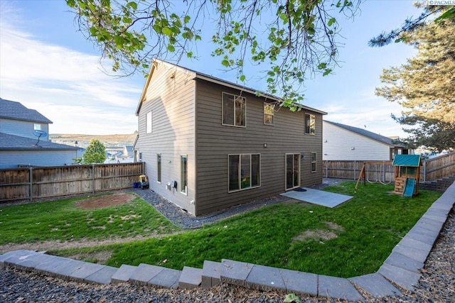 back of property featuring a lawn, a playground, and a fenced backyard