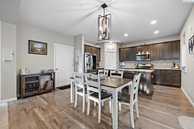 dining area featuring light wood-style floors, baseboards, an inviting chandelier, and recessed lighting