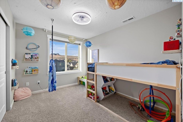 carpeted bedroom with visible vents, a textured ceiling, and baseboards