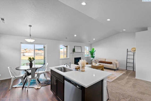 kitchen with a sink, vaulted ceiling, light countertops, stainless steel dishwasher, and a glass covered fireplace