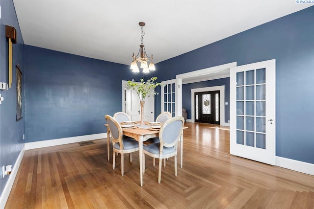 dining room featuring parquet flooring, french doors, and a chandelier