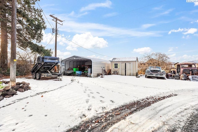 snowy yard featuring a carport and a storage unit