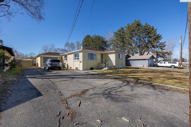 ranch-style home featuring driveway, stucco siding, and fence