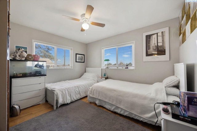 bedroom with multiple windows, a ceiling fan, and wood finished floors