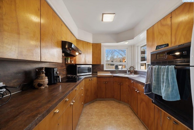 kitchen with black appliances, a sink, dark countertops, brown cabinets, and extractor fan