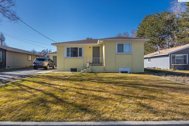 bungalow featuring stucco siding and a front lawn