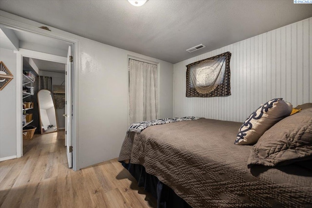 bedroom with wooden walls, visible vents, and wood finished floors
