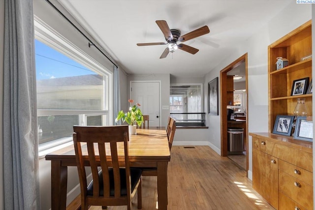 dining room featuring light wood-style flooring, visible vents, baseboards, and ceiling fan