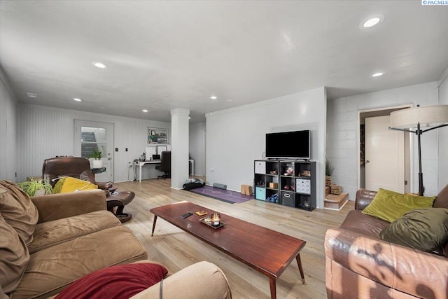 living room featuring ornate columns, light wood finished floors, concrete block wall, and recessed lighting
