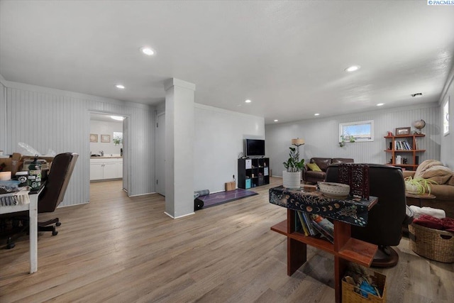 living room with light wood-style floors, ornamental molding, and recessed lighting