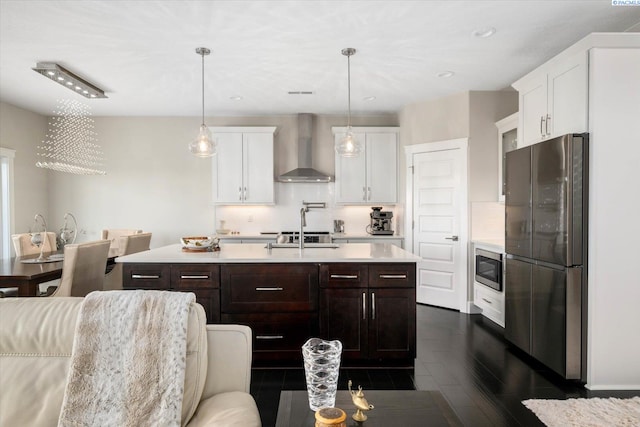 kitchen featuring light countertops, decorative backsplash, appliances with stainless steel finishes, white cabinetry, and wall chimney exhaust hood