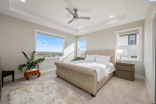 bedroom with a tray ceiling, recessed lighting, light colored carpet, and baseboards