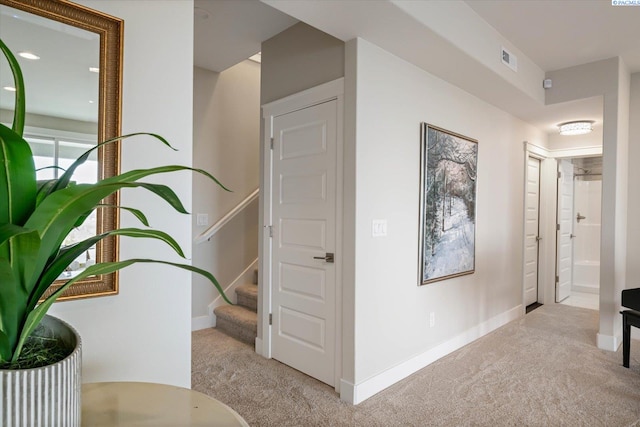 hallway featuring carpet floors, baseboards, stairs, and visible vents