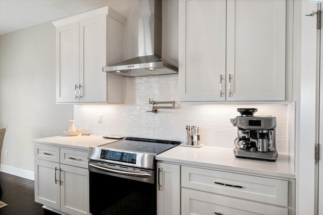 kitchen with light countertops, wall chimney range hood, backsplash, and stainless steel electric stove