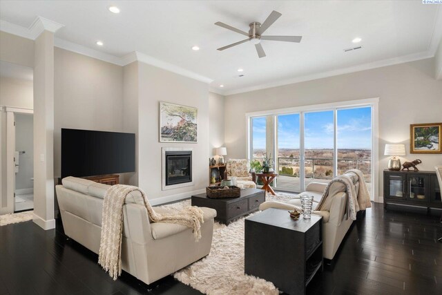 living area with dark wood-type flooring, a glass covered fireplace, and crown molding