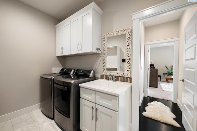 clothes washing area featuring a sink, baseboards, marble finish floor, cabinet space, and washing machine and clothes dryer