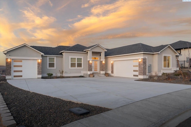 prairie-style house with stone siding, driveway, an attached garage, and stucco siding