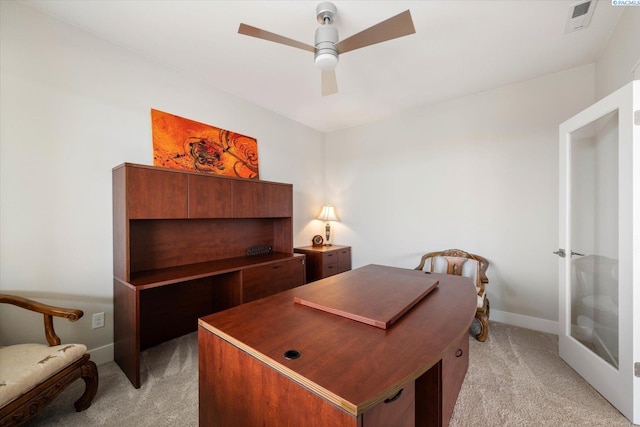 office space with a ceiling fan, light colored carpet, visible vents, and baseboards