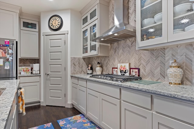 kitchen with light stone counters, white cabinetry, stainless steel appliances, and wall chimney exhaust hood