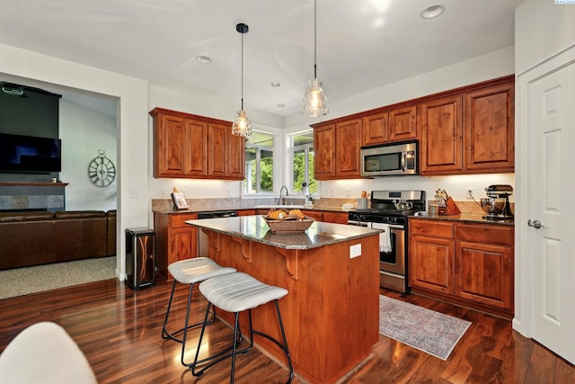 6117 Dorchester Ct, Pasco, WA 99301 - kitchen featuring stainless steel appliances, a kitchen island, a kitchen bar, dark stone countertops, and dark wood-type flooring