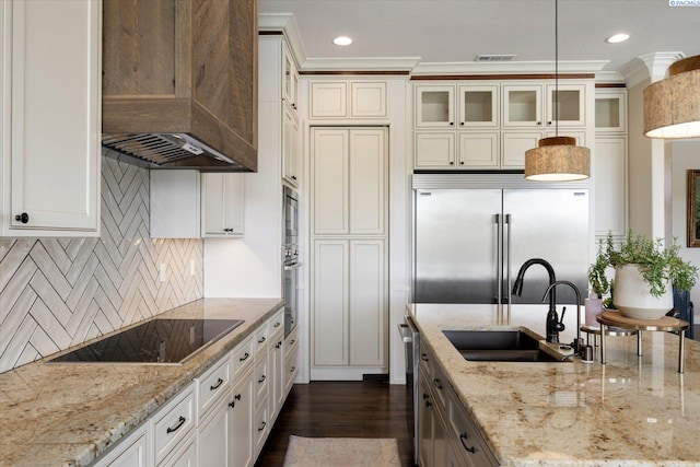 kitchen with built in appliances, premium range hood, a sink, glass insert cabinets, and decorative backsplash
