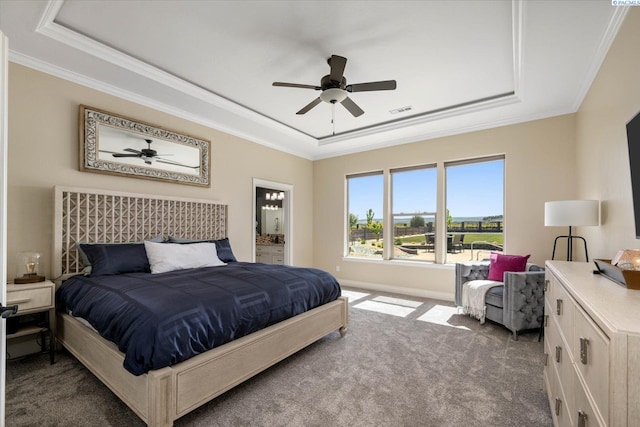 carpeted bedroom with a raised ceiling, crown molding, connected bathroom, baseboards, and ceiling fan