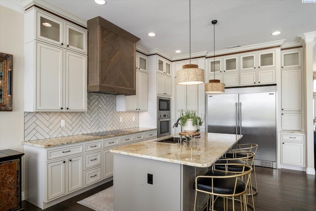 kitchen featuring black appliances, a sink, an island with sink, backsplash, and light stone counters