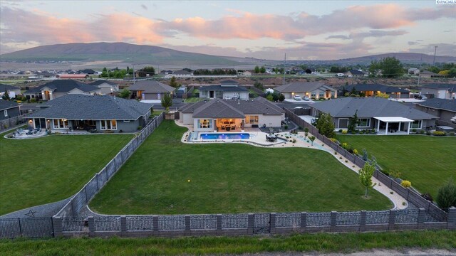 aerial view at dusk of a residential view, a mountain view, and view of pool