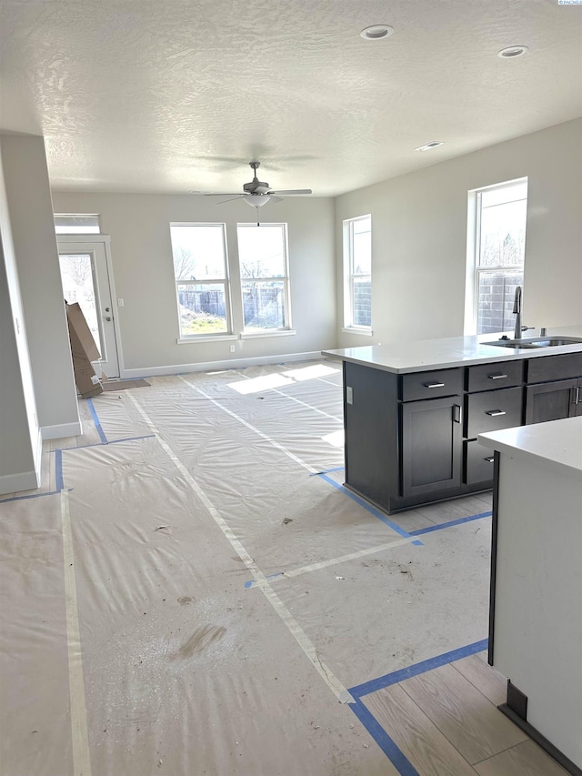 kitchen with open floor plan, light countertops, a sink, and baseboards