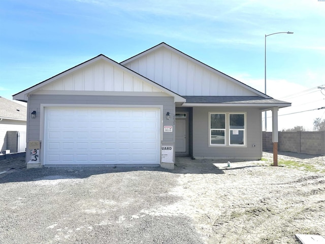 ranch-style house with a garage, roof with shingles, fence, and board and batten siding