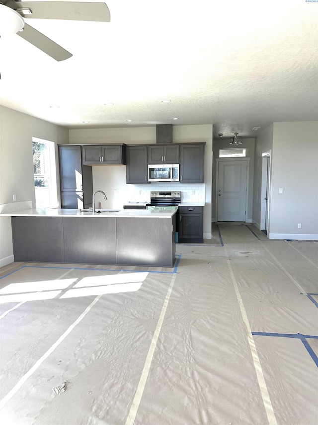 kitchen with ceiling fan, baseboards, light countertops, backsplash, and stainless steel microwave