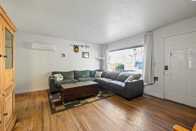 living room with dark wood-type flooring, a wall mounted air conditioner, and a textured ceiling