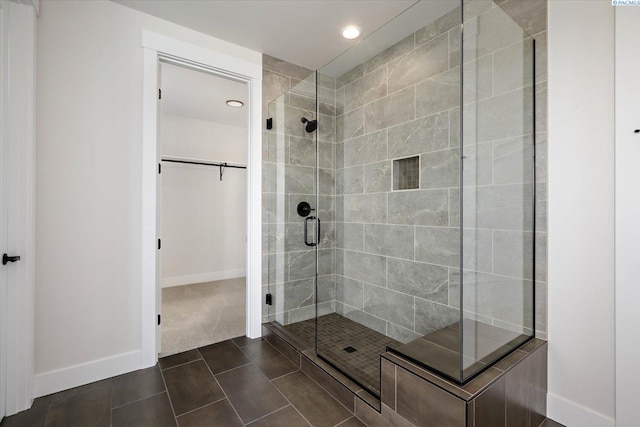 bathroom featuring baseboards, a walk in closet, a stall shower, and recessed lighting