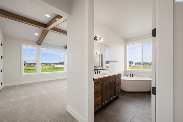 bathroom with beam ceiling, baseboards, vanity, and a soaking tub