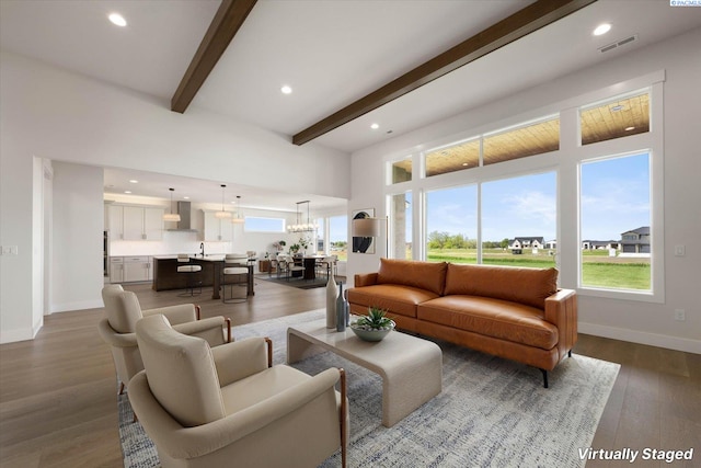 living area with dark wood-type flooring, beamed ceiling, baseboards, and visible vents