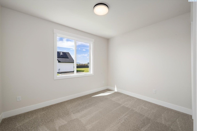 carpeted empty room featuring baseboards