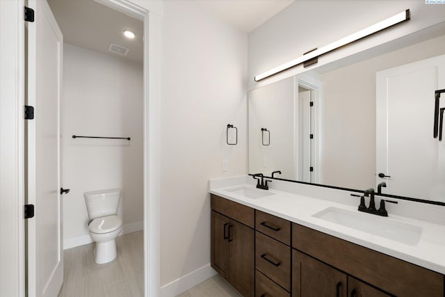 bathroom featuring a sink, visible vents, toilet, and double vanity