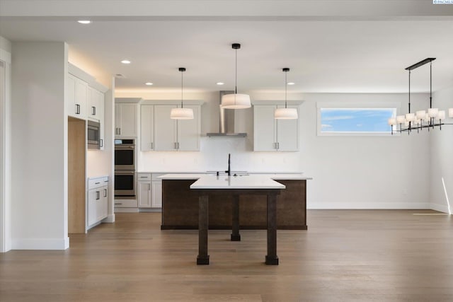 kitchen with a kitchen island with sink, wall chimney exhaust hood, baseboards, and stainless steel appliances