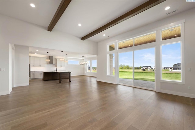 unfurnished living room with visible vents, baseboards, beam ceiling, and dark wood finished floors