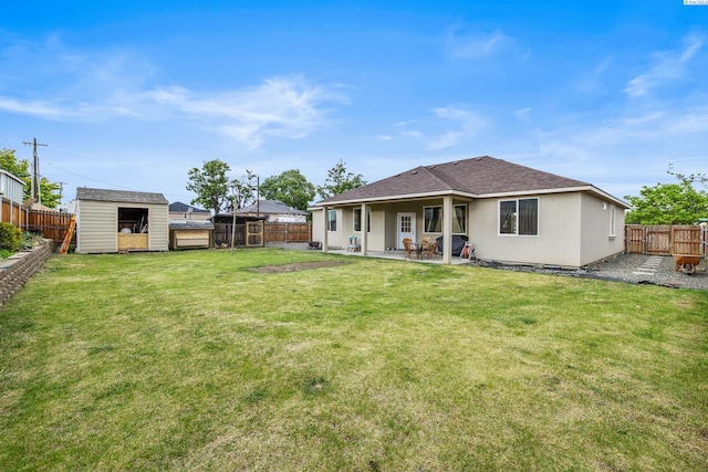 rear view of property featuring a patio area, a storage unit, an outbuilding, roof with shingles, and stucco siding