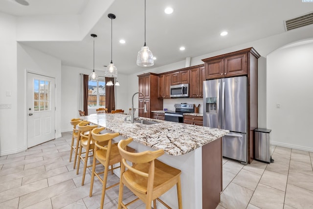 kitchen featuring appliances with stainless steel finishes, a sink, a kitchen breakfast bar, light tile patterned floors, and recessed lighting