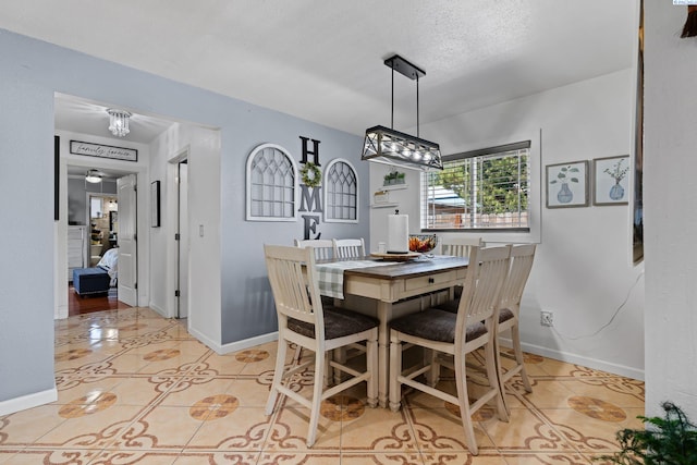 dining space with baseboards, a textured ceiling, and light tile patterned flooring