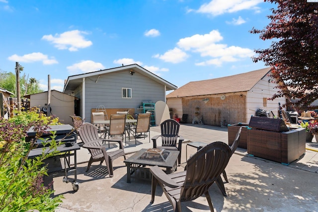 view of patio / terrace featuring outdoor dining area, a fire pit, an outbuilding, and a storage unit