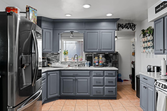 kitchen with gray cabinets, tasteful backsplash, a sink, stainless steel appliances, and light tile patterned flooring