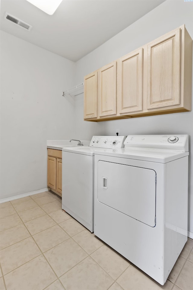 laundry room with independent washer and dryer, cabinets, and light tile patterned flooring