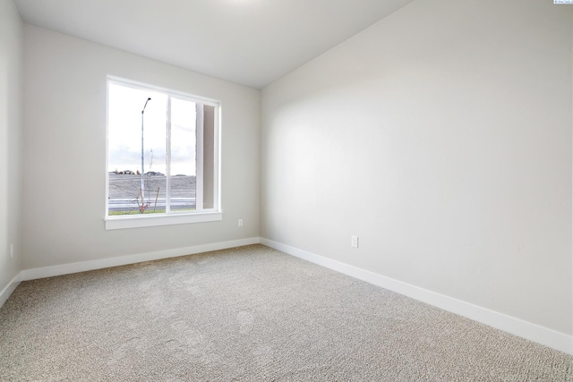 carpeted spare room with lofted ceiling