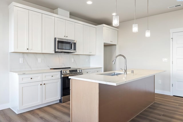 kitchen with appliances with stainless steel finishes, sink, a center island with sink, and white cabinets