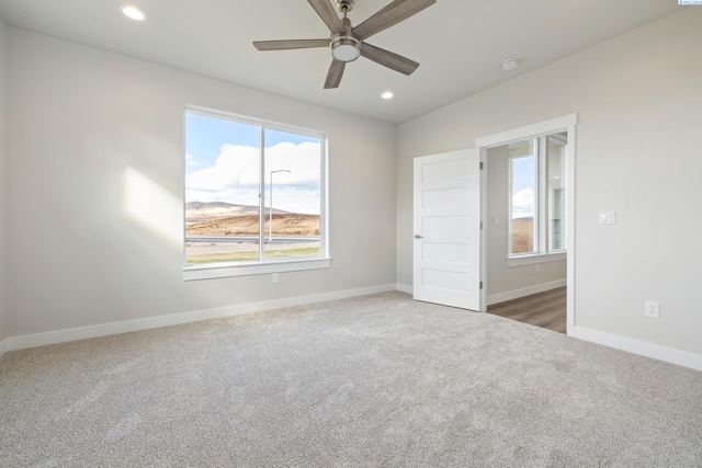 carpeted spare room featuring ceiling fan