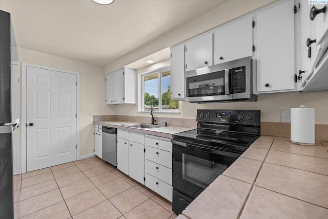 1807 Stevens Dr, Richland, WA 99354 - kitchen featuring black appliances, a sink, tile counters, light tile patterned flooring, and white cabinets