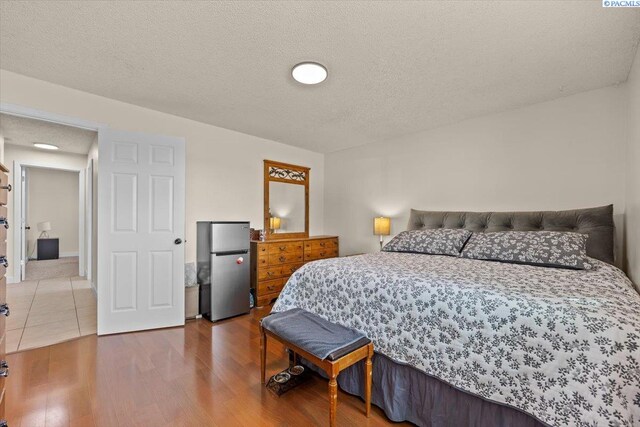 1807 Stevens Dr, Richland, WA 99354 - bedroom featuring freestanding refrigerator, wood finished floors, and a textured ceiling